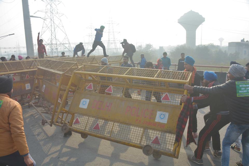 NEW DELHI, INDIA - JANUARY 26: Demonstrators breaking past police barricades while heading into the capital during a tractor rally on Republic Day, at Ghazipur on January 26, 2021 in New Delhi, India. Major scenes of chaos and mayhem at Delhi borders as groups of farmers allegedly broke barricades and police check posts and entered the national capital before permitted timings. Police used tear gas at Delhi's Mukarba Chowk to bring the groups under control. Clashes were also reported at ITO, Akshardham. Several rounds of talks between the government and protesting farmers have failed to resolve the impasse over the three farm laws. The kisan bodies, which have been protesting in the national capital for almost two months, demanding the repeal of three contentious farm laws have remained firm on their decision to hold a tractor rally on the occasion of Republic Day. (Photo by Sakib Ali/Hindustan Times via Getty Images)