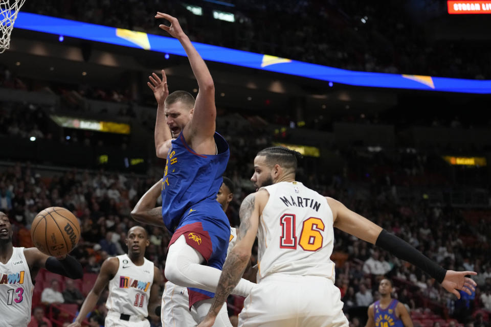 Denver Nuggets center Nikola Jokic, center, loses control of the ball as Miami Heat forward Caleb Martin (16) defends during the first half of an NBA basketball game, Monday, Feb. 13, 2023, in Miami. (AP Photo/Lynne Sladky)