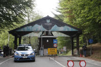 A police car drives past a sign reading in Italian "Road closed for transit" as the road leading to the Stresa-Mottarone cable line is closed off in order for rescue operations to take place after a cable car of the line collapsed, near Stresa, Italy, Sunday, May 23, 2021. A cable car taking visitors to a mountaintop view of some of northern Italy's most picturesque lakes plummeted to the ground Sunday and then tumbled down the slope, killing at least 13 people and sending two children to the hospital, authorities said. (AP Photo/Antonio Calanni)