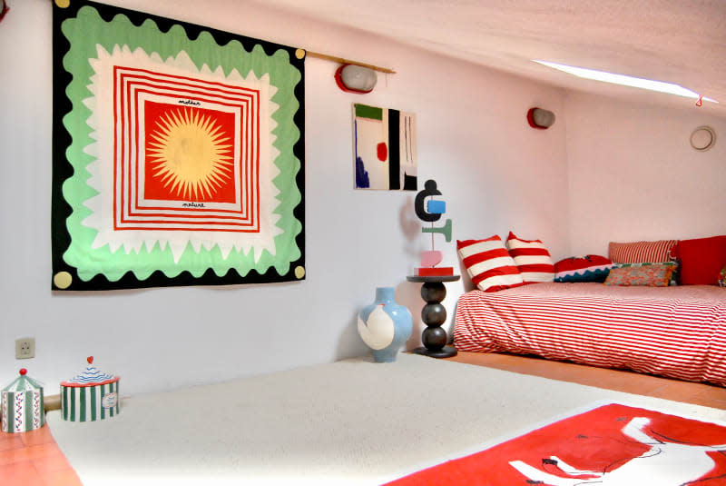 Tapestry artwork hung on wall next to bed with red striped bedding.