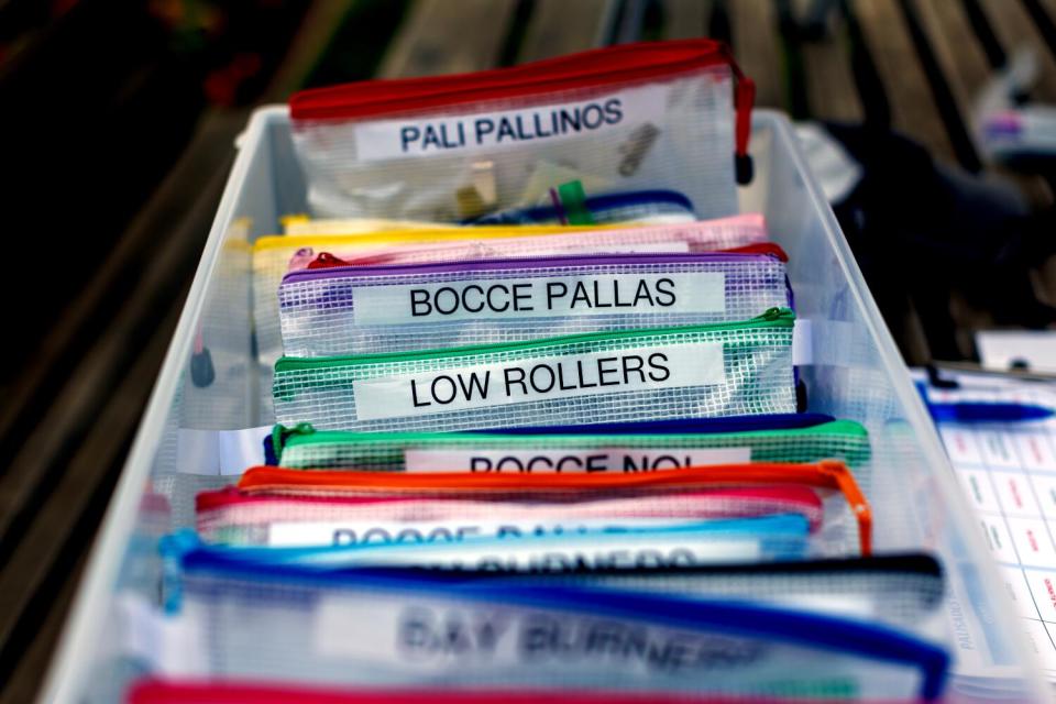 A bin full of individual bags, labelled with bocce team names.