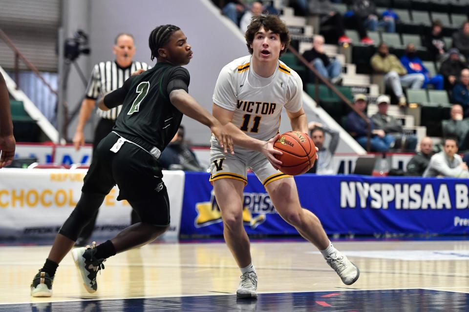 Victor's Cam Ryan, right, is defended by Brentwood's Jerimiah Webb during a NYSPHSAA Class AA Boys Basketball Championship semifinal in Glens Falls, N.Y., Friday, March 17, 2023. Victor advanced to the Class AA title game with a 56-41 win over Brentwood-XI.