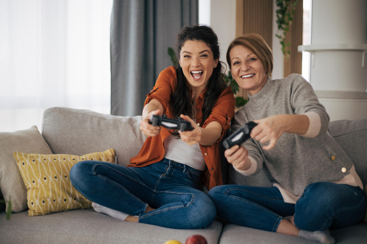 Mother and daughter having fun together. Playing video games and sitting on the sofa.