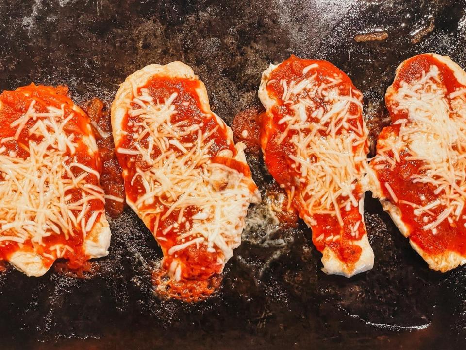 four pieces of chicken covered in tomato sauce and mozzarella cheese