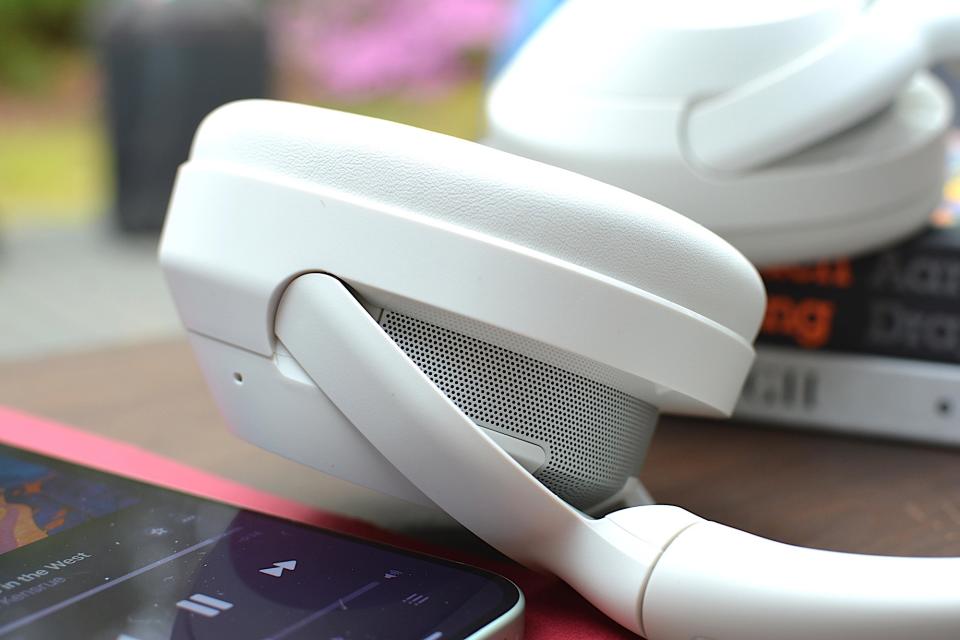 Headband and ear cup detail of a set of white headphones showing speaker grille design.