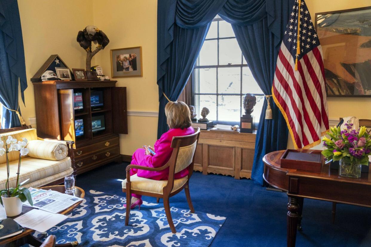 A woman sits in an office watching television