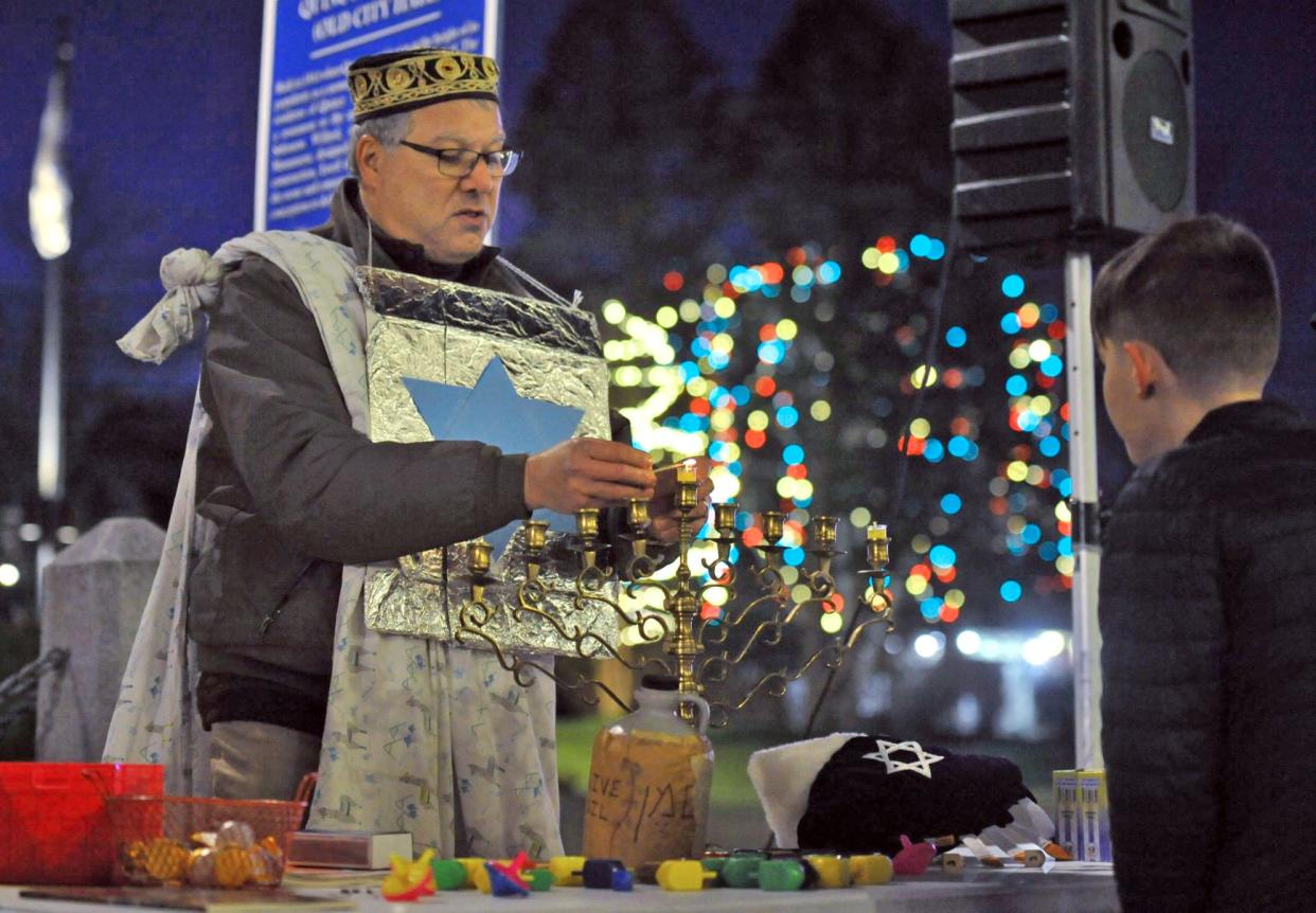 Rabbi Alfred Benjamin, of the Congregation Beth Shalom of the Blue Hills in Milton, lights a small menorah at the Hancock Adams Common in Quincy on the first night of Hanukkah, Sunday, Dec. 18, 2022.