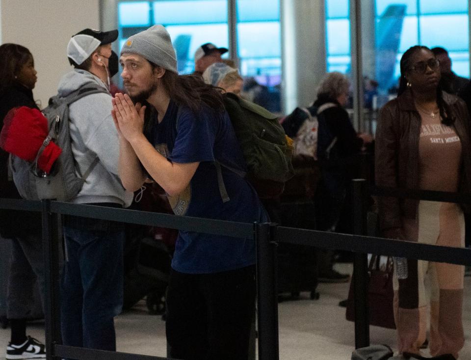 Will Ringer clasps his hands as he look as the screens showing flight delays and cancellations at Nashville International Airport on Tuesday.