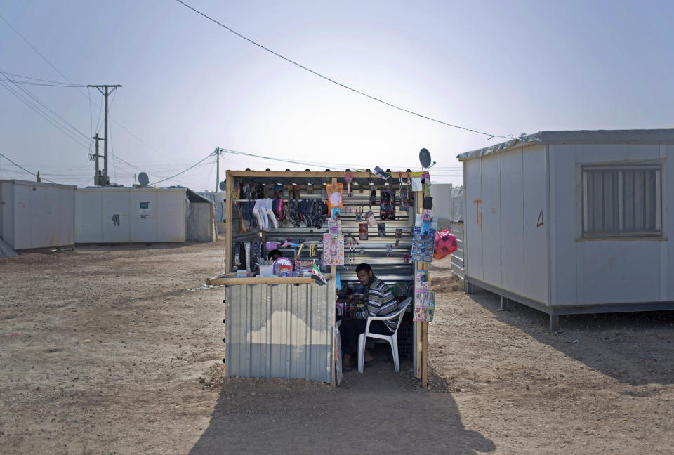 In Thursday April 17, 2014 photo, Syrian refugee Abu Mohammed sits in a shop he has set up to sell women's accessories to boost his non-existent income at Zaatari refugee camp, near the Syrian border in Jordan. It was hard enough for Abu Mohammed to flee his hometown of Daraa in southern Syria because of the raging fighting. He now has to survive on basics in this sprawling refugee camp in Jordan, and pay rent to a fellow Syrian strongman for the use of a small plot of land to set up a shop.(AP Photo/Khalil Hamra)