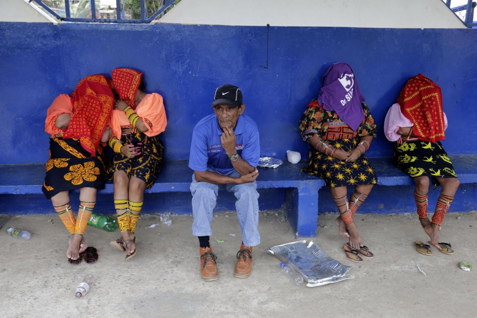 Guna indigenous women cover their faces outside at a polling station in Loma Cova on the outskirts of Panama City, Sunday, May 4, 2014. Panamanians are choosing a new president in a three-way dogfight marked more by ugly personality clashes between the candidates, than any deep disagreements over the way forward for Latin America's standout economy. (AP Photo/Tito Herrera)