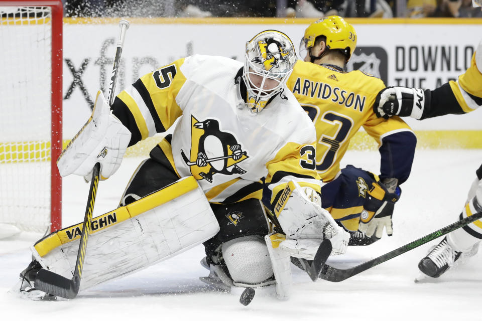 Pittsburgh Penguins goaltender Tristan Jarry (35) grabs the puck as Nashville Predators right wing Viktor Arvidsson (33), of Sweden, slides by during the second period of an NHL hockey game Friday, Dec. 27, 2019, in Nashville, Tenn. (AP Photo/Mark Humphrey)