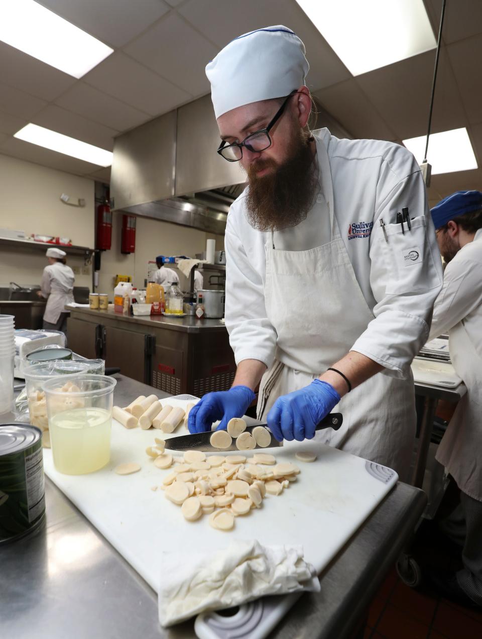 Sullivan University student Jake Jolly chops hearts of palm as they prepare a full course meal at the school in Louisville, Ky. on Apr. 23, 2023.  The Courier Journal donated decades of archived recipes to the university which is preparing a meal using those recipes to honor the past food editors.