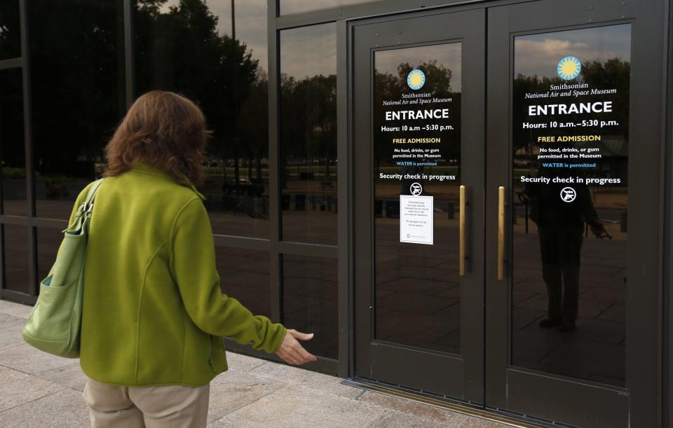 Fernanda Wagstaff holds her hand out in disbelief as she reads a sign at the Air and Space Museum informing visitors that all Smithsonian museums are closed, in Washington October 1, 2013. The U.S. government partially shut down for the first time in 17 years on Tuesday as a standoff between President Barack Obama and congressional Republicans over healthcare reforms closed many government offices, museums and national parks and slowed everything from trade negotiations to medical research. REUTERS/Kevin Lamarque (UNITED STATES - Tags: POLITICS BUSINESS)