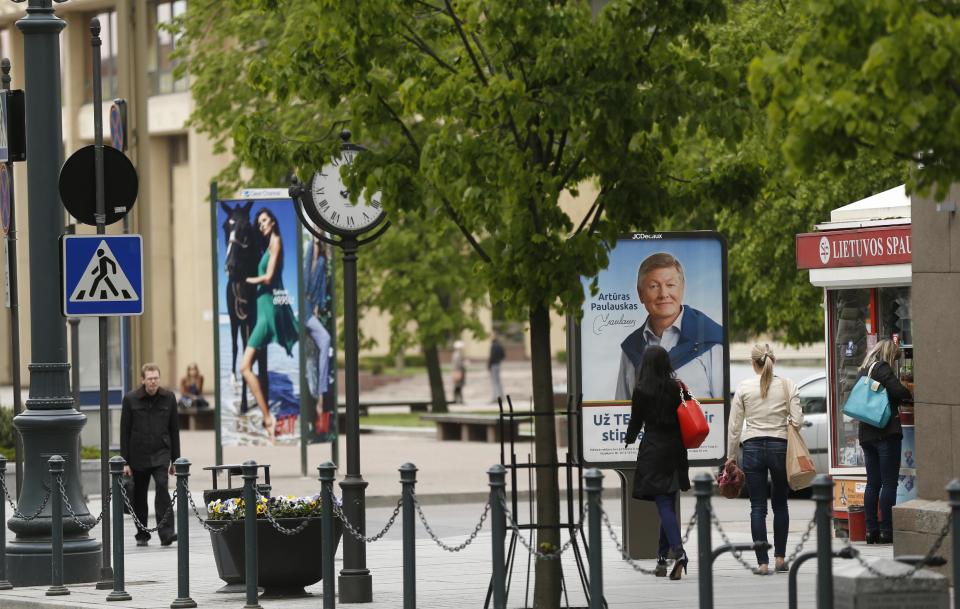 A local resident walks by an election poster showing Lithuanian Labour Party leader Arturas Paulauskas, a presidential candidate, in Vilnius, Lithuania, Friday, May 9, 2014. Lithuanians will ballot Sunday, May 11, in a first round of presidential elections. (AP Photo / Mindaugas Kulbis)