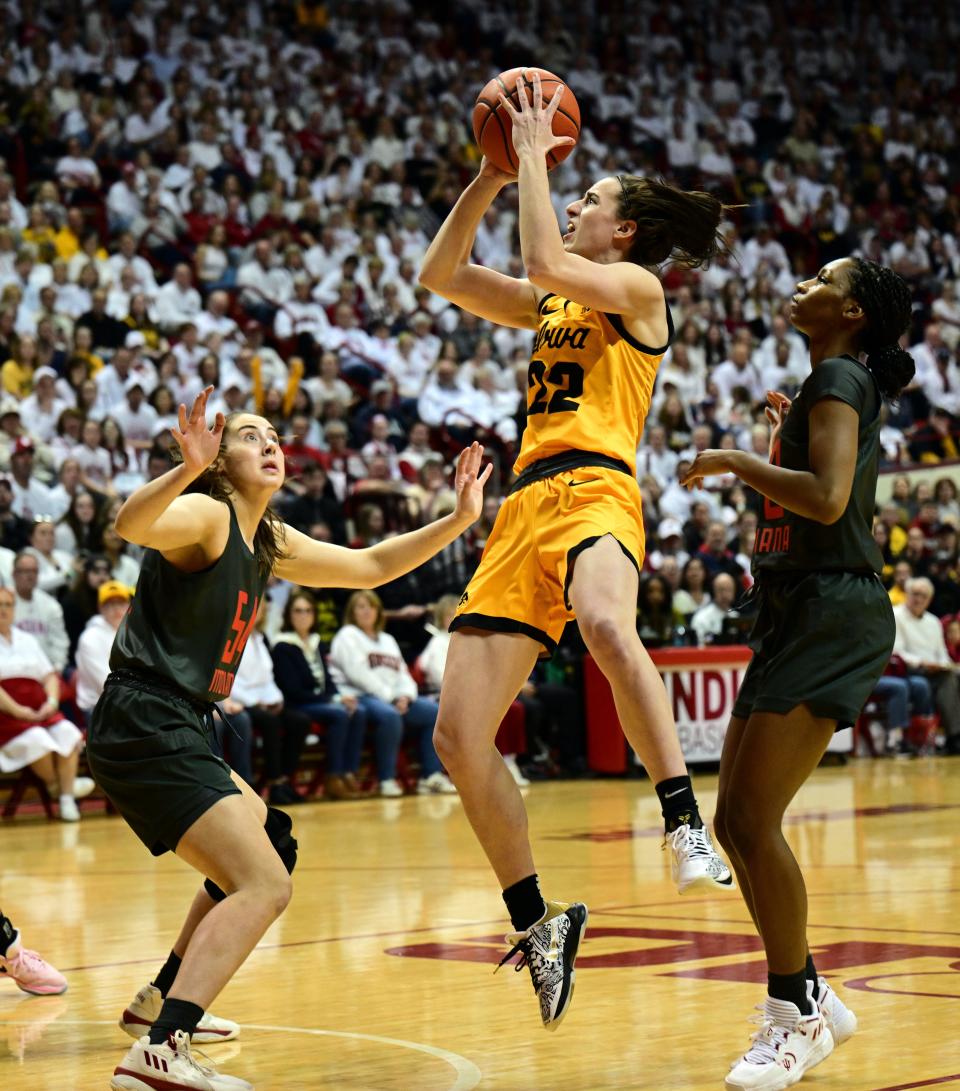 Feb 22, 2024; Bloomington, Indiana, USA; Iowa Hawkeyes guard Caitlin Clark (22) shoots the ball between Indiana Hoosiers forward Mackenzie Holmes (54), left, and guard Chloe Moore-McNeil (22), right, during the fist quarter at Simon Skjodt Assembly Hall. Mandatory Credit: Marc Lebryk-USA TODAY Sports