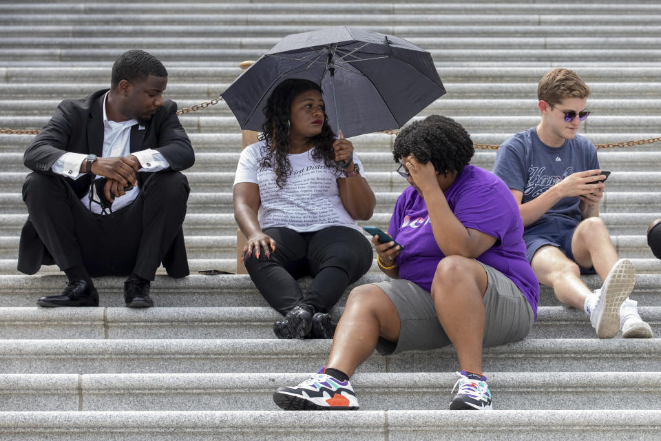 Rep. Cori Bush, D-Mo., second from left, sits with supporters advocating for reinstating the now-expired nationwide eviction moratorium sit outside of Capitol Hill in Washington on Tuesday, Aug. 3, 2021. Bush has been camped outside the U.S. Capitol in protest since the weekend. She was joined overnight Monday by Ocasio-Cortez, Rep. Jimmy Gonzalez, D-Calif., and others who gave her a brief reprieve so she could rest indoors. Bush also had a brief conversation Monday at the Capitol with Vice President Kamala Harris. (AP Photo/Amanda Andrade-Rhoades)