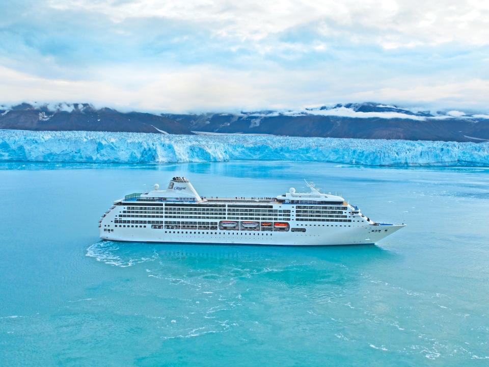 The Regent Seven Seas Mariner cruise ship sailing past a glacier.