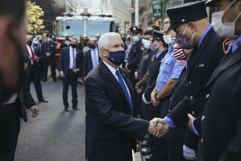 Vice President Mike Pence greets firefighters assembled at FDNY Ladder 10 Engine 10 near the 9/11 Memorial on Friday, Sept. 11, 2020, in New York. Americans are commemorating 9/11 with tributes that have been altered by coronavirus precautions and woven into the presidential campaign, drawing President Donald Trump and Democratic challenger Joe Biden to pay respects at the same memorial without crossing paths.(AP Photo/Kevin Hagen).