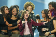 Twenty year old Kelly Clarkson (C) of Burleston, Texas, winner in the competition of the television reality music program "American Idol" sings "A Moment Like This" to end the telecast September 4, 2002 at the Kodak Theatre in Hollywood as she is congratulated by fellow contestants (L-R) Ryan Starr, Tamyra Gray, Justin Guarini, Christina Christian, Nikki McKibbin and Ejay Day. Clarkson wins a recording contract and will also tour the country performing with the other American Idol contestants. The contestants reunite for a television special "American Idol in Las Vegas which will be telecast September 23. BEST QUALITY AVAILABLE REUTERS/Fred Prouser FSP