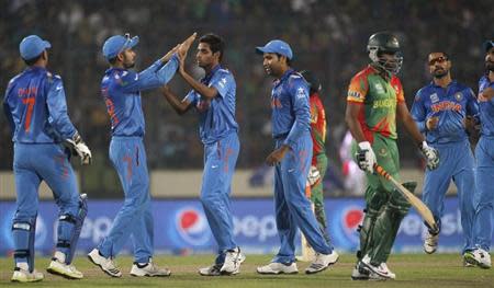 Bangladesh's Shakib Al Hasan leaves the field as India's fielders congratulate Bhuvneshwar Kumar (3rd L) for dismissing him successfully during their ICC Twenty20 World Cup match at the Sher-E-Bangla National Cricket Stadium in Dhaka March 28, 2014. REUTERS/Andrew Biraj