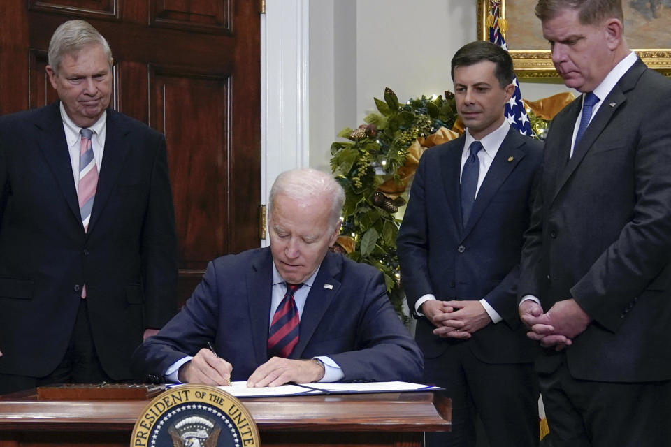 President Joe Biden signs H.J.Res.100, a bill that aims to avert a freight rail strike, in the Roosevelt Room at the White House, Friday, Dec. 2, 2022, in Washington. Biden is joined by from left, Agriculture Secretary Tom Vilsack, Transportation, Secretary Pete Buttigieg and and Secretary of Labor Marty Walsh. / Credit: Manuel Balce Ceneta / AP