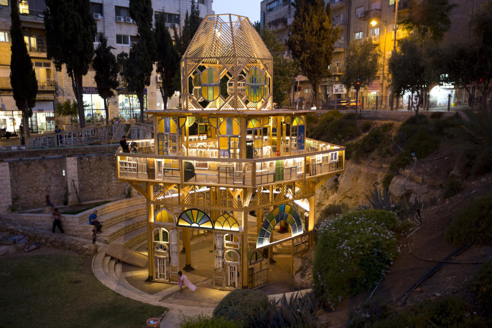 In this Tuesday, July 16, 2019 photo, people visit an art installation in Jerusalem. The project in downtown Jerusalem is using a tower of old windows to give a view of the city’s diverse cultural past and present and bring life to a neglected area. “Window Stories” is made of 500 windows collected by the late Jerusalem artist Yoram Amir, who organizers said was “madly in love” with the city and its many ethnic and religious communities. (AP Photo/Dusan Vranic)