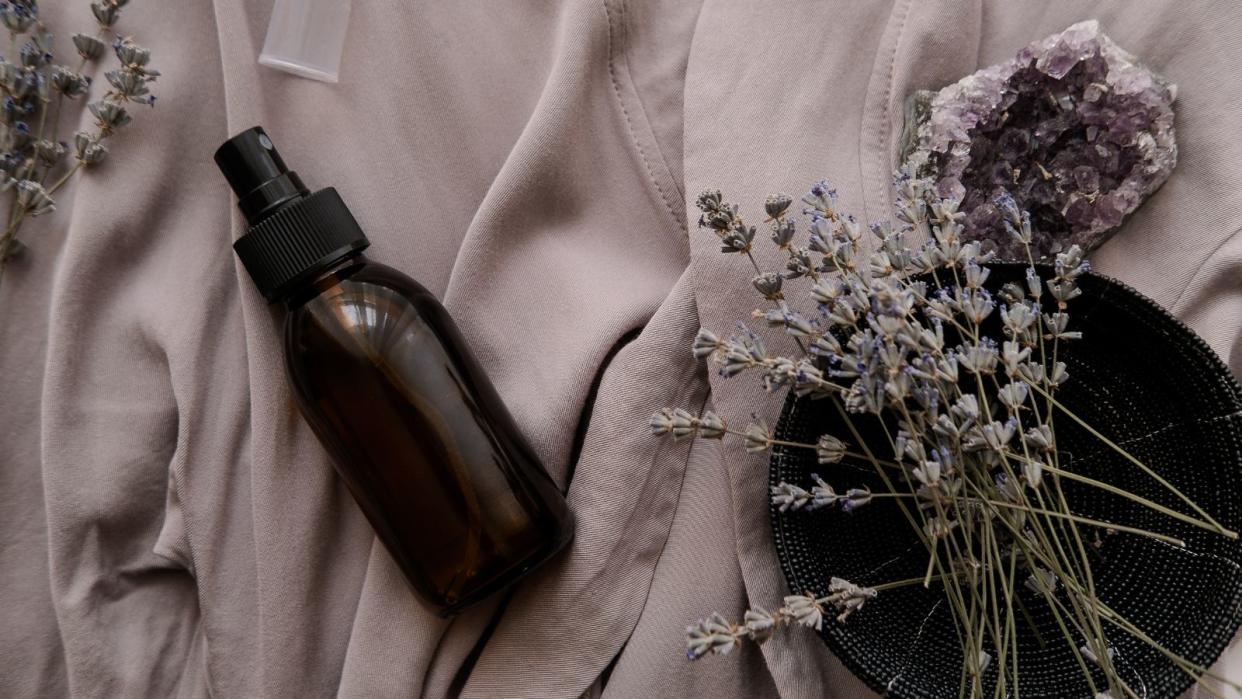  Amber glass bottle on a purple towel with dried flowers 