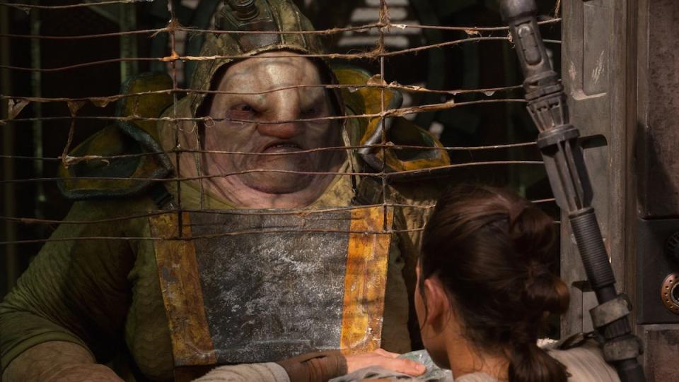 The oversized alien Unkar Plutt talks to Rey from behind a mesh screen in The Force Awakens