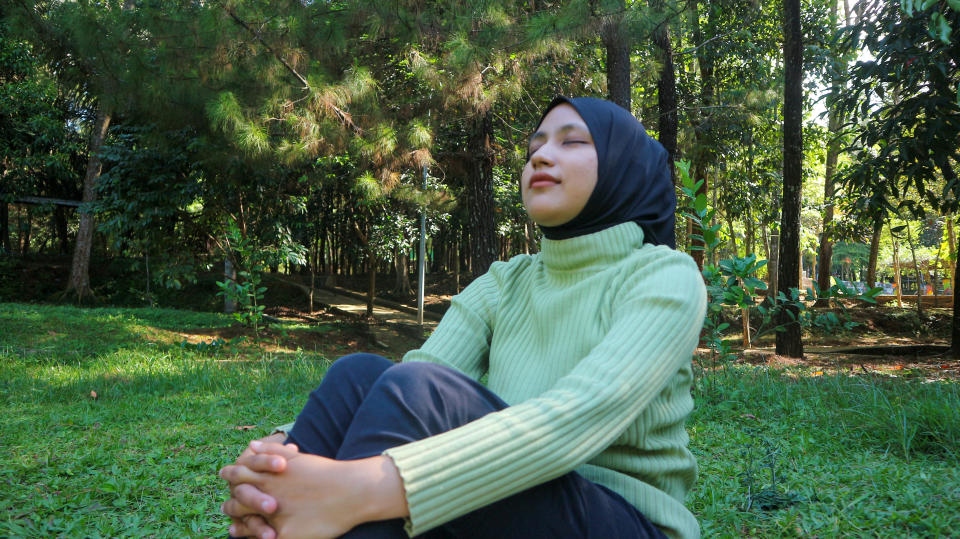 muslim woman looking serene in a park while sitting on grass
