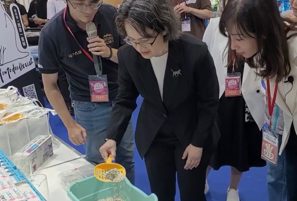蕭美琴在寵物用品展上示範如何剷貓砂。總統府記者聯誼會提供