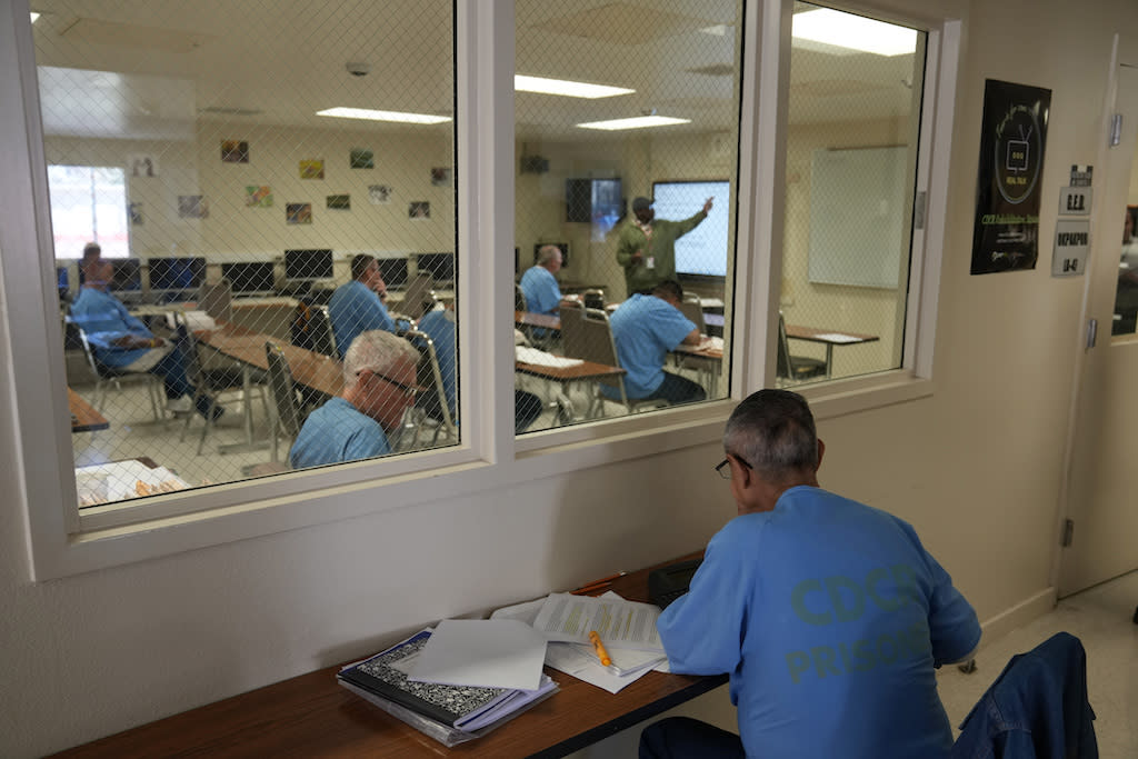 Men in blue prison fatigues in a classroom