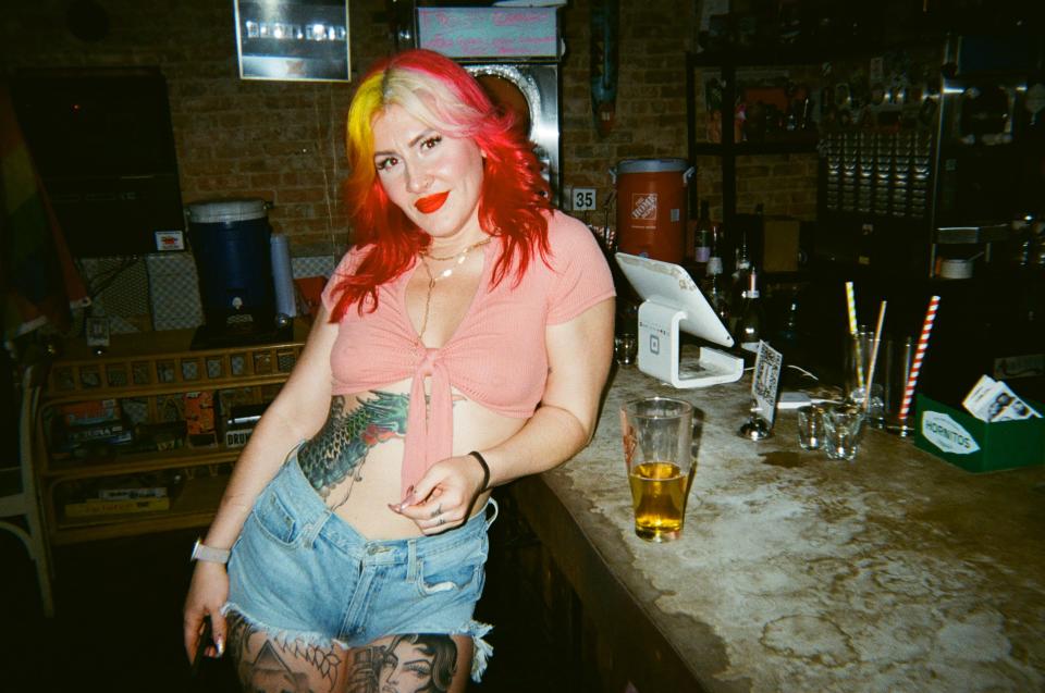 woman with colorful hair and tattoos inside of a bar