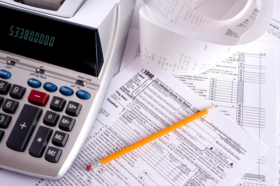 A tax form under an adding machine and pencil.