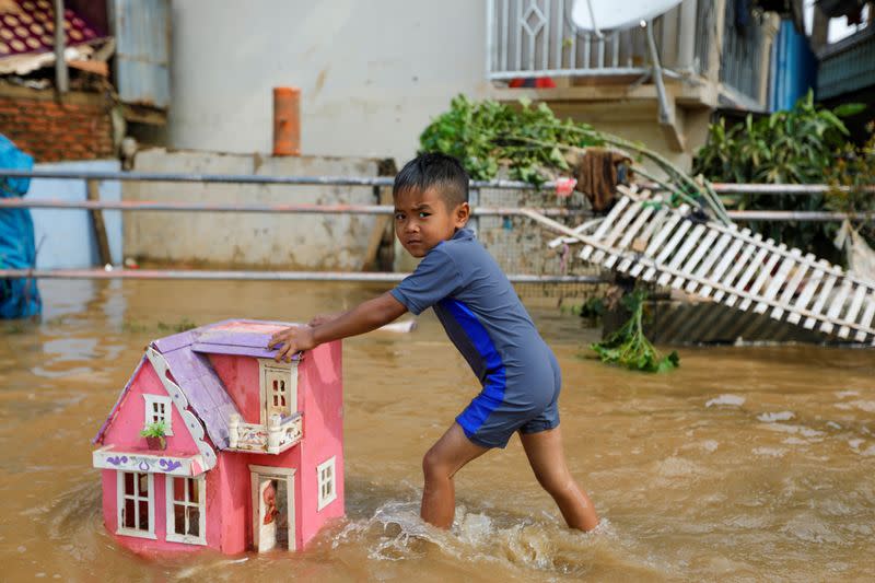 A boy pushes a toy house as he plays in floodwaters after heavy rains in Jakarta