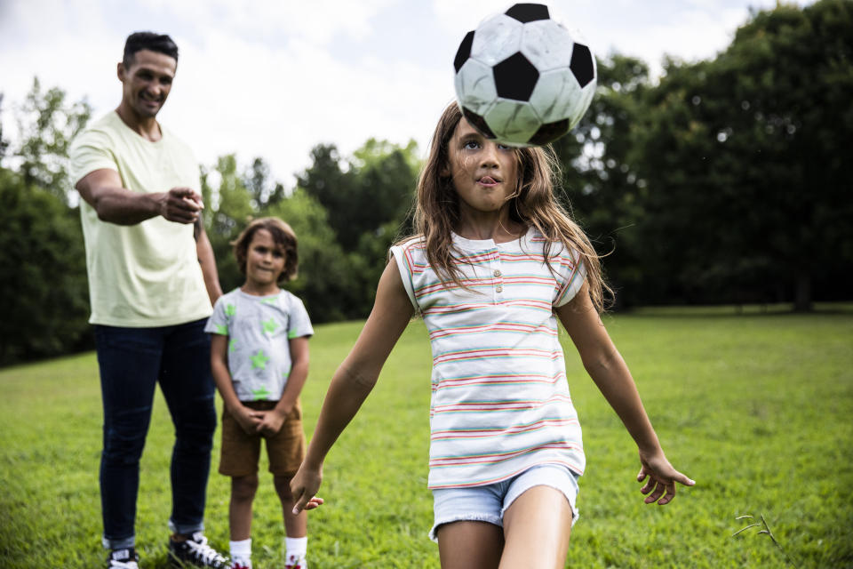 A parent and their kids playing soccer