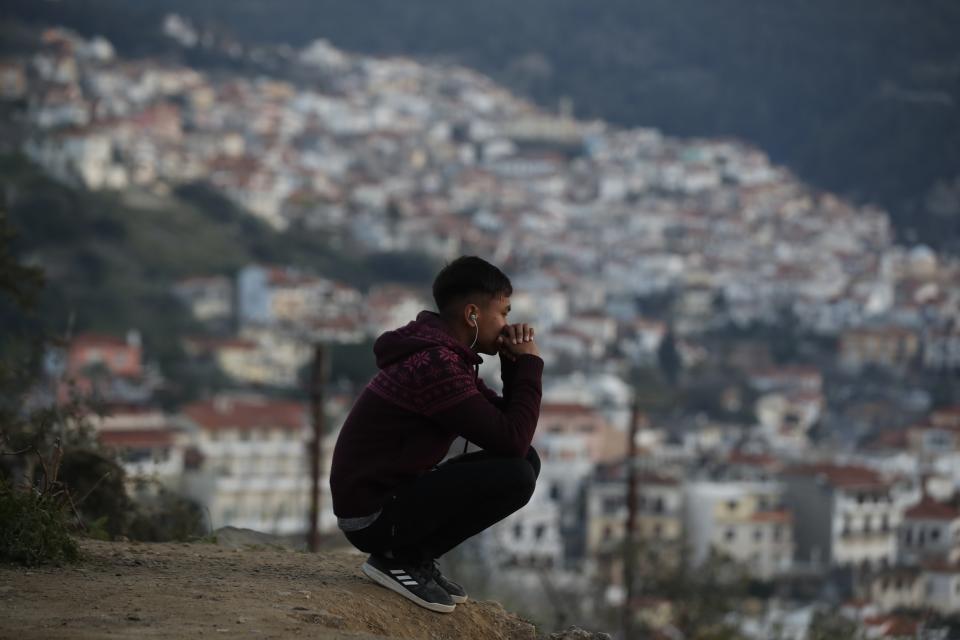 A migrant sits on a hill outside the perimeter of the overcrowded refugee camp at the port of Vathy on the eastern Aegean island of Samos, Greece, Tuesday, Feb. 23, 2021. On a hill above a small island village, the sparkling blue of the Aegean just visible through the pine trees, lies a boy’s grave. His first ever boat ride was to be his last - the sea claimed him before his sixth birthday. His 25-year-old father, like so many before him, had hoped for a better life in Europe, far from the violence of his native Afghanistan. But his dreams were dashed on the rocks of Samos, a picturesque Greek island almost touching the Turkish coast. Still devastated from losing his only child, the father has now found himself charged with a felony count of child endangerment. (AP Photo/Thanassis Stavrakis)