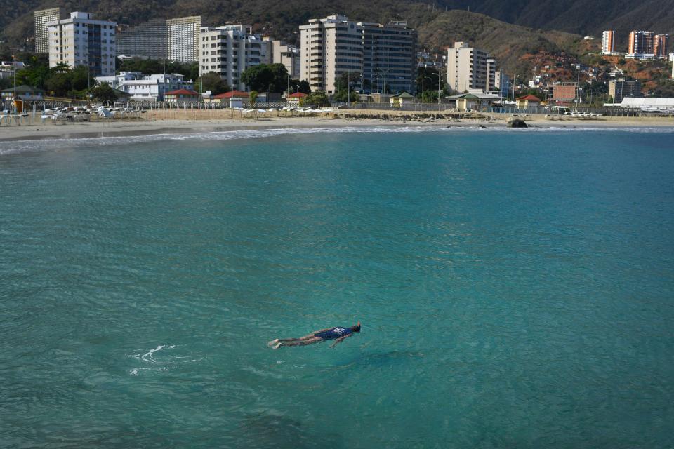 A man swims in the beach Los Corales, in La Guaira, Venezuela, Saturday, March 21, 2020.