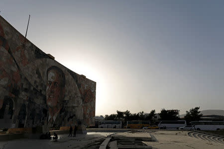 People rest in front of a picture of former Syrian President Hafez al-Assad at Harasta highway outside Jobar, in Damascus, Syria March 26, 2018. REUTERS/Omar Sanadiki