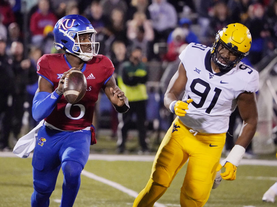 Kansas quarterback Jalon Daniels (6) looks to pass against West Virginia defensive lineman Sean Martin (91) during the first quarter of an NCAA college football game Saturday, Nov. 27, 2021, in Lawrence, Kan. (AP Photo/Ed Zurga)