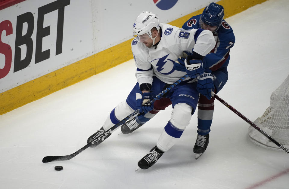 Tampa Bay Lightning defenseman Erik Cernak, left, fights for control of the puck with Colorado Avalanche defenseman Devon Toews in the first period of an NHL hockey game, Tuesday, Feb. 14, 2023, in Denver. (AP Photo/David Zalubowski)