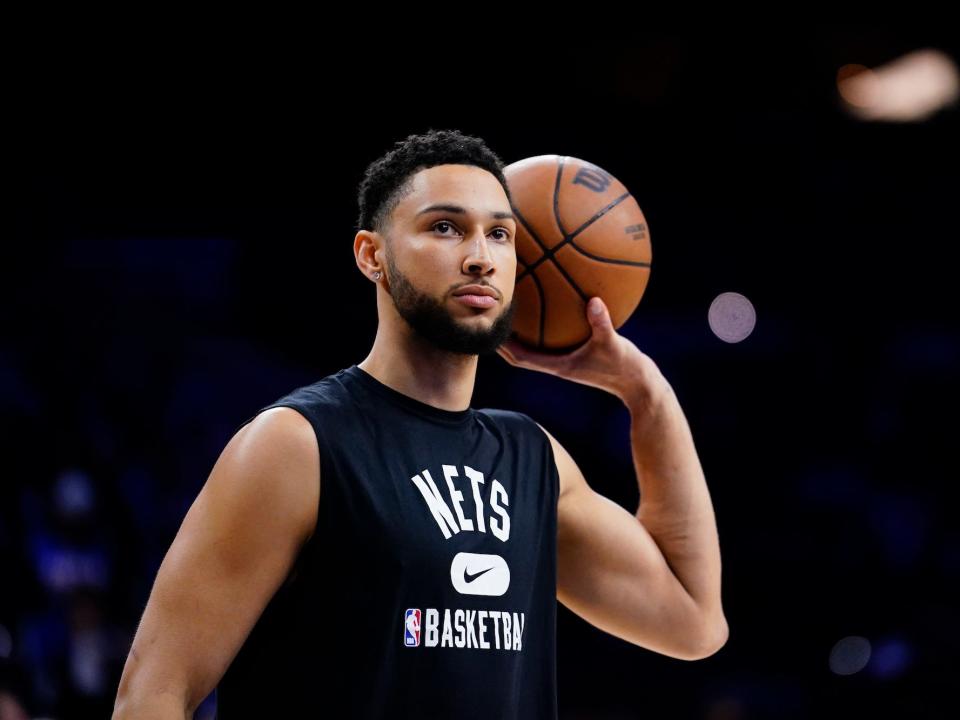 Ben Simmons holds a basketball and looks up during Nets warmups.
