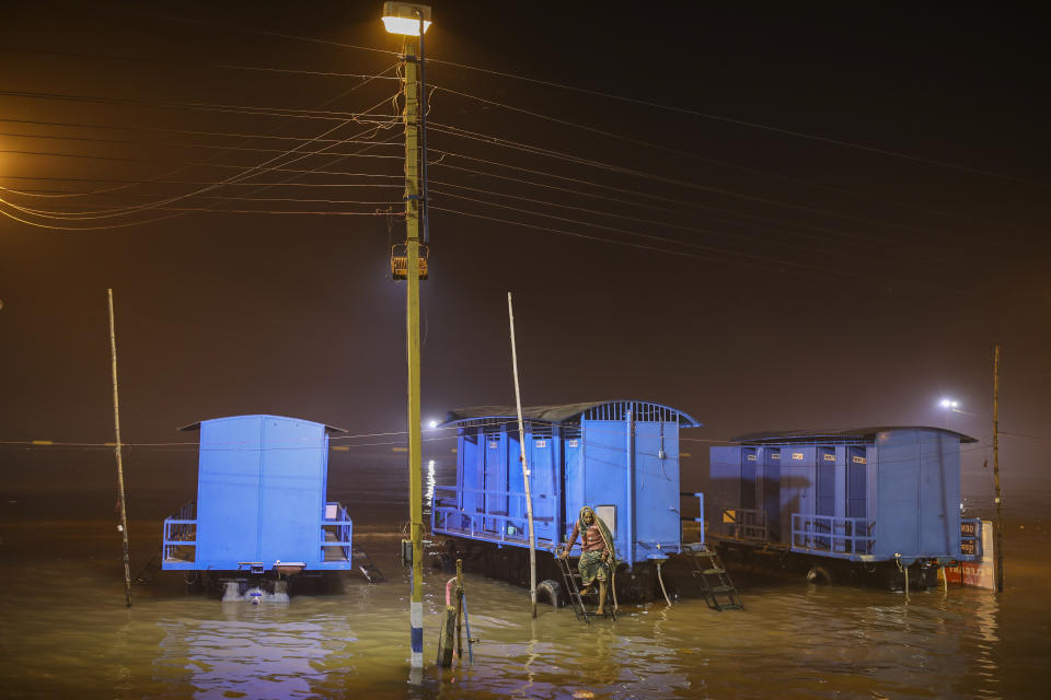 A Hindu pilgrim is stranded on a mobile toilet after high tide submerged the camping area for pilgrims on the eve of Makar Sankranti festival on Sagar Island, an island lying in the Ganges delta, India, Monday, Jan. 13, 2020. Sagar and many other small islands which are part of the Sundarbans, the world's largest mangrove forest, have seen a dramatic rise in sea levels due to climate change. The highest point in the Sundarbans is around 3 meters (9.8 feet) and the mean elevation is less than a meter above sea level. (AP Photo/Altaf Qadri)