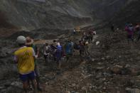 Rescue workers use poles to carry bodies shrouded in blue and red plastic sheets Thursday, July 2, 2020 in Hpakant, Kachin State, Myanmar. At least 162 people were killed Thursday in a landslide at a jade mine in northern Myanmar, the worst in a series of deadly accidents at such sites in recent years that critics blame on the government's failure to take action against unsafe conditions. (AP Photo / Zaw Moe Htet)