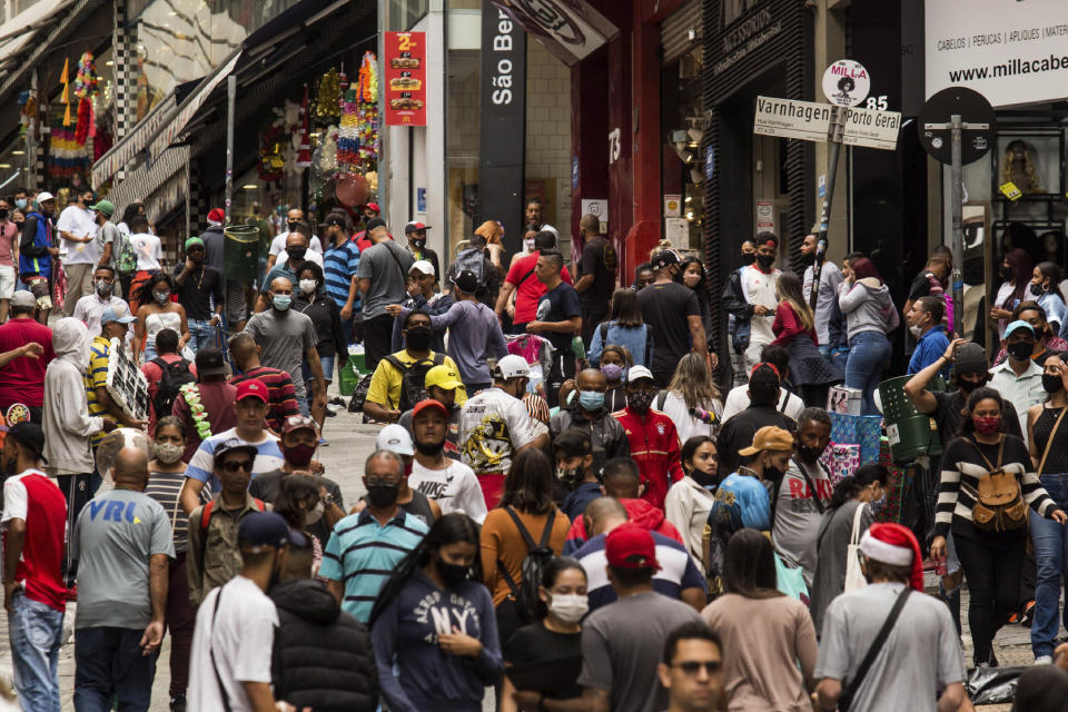 People shop along the street "25 de Marco," an outdoor market area, days before a COVID-19 lockdown goes into effect in Sao Paulo, Brazil, Wednesday, Dec. 23, 2020. Only essential business will be allowed to operate from Dec. 25 - 27 and Jan. 1 - 3. (AP Photo/Carla Carniel)