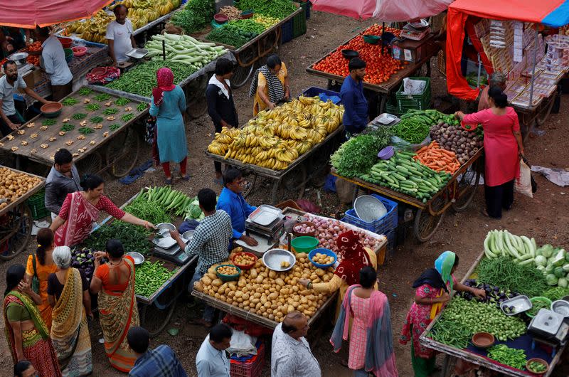 Customers buy fruits and vegetables at an open air evening market in Ahmedabad