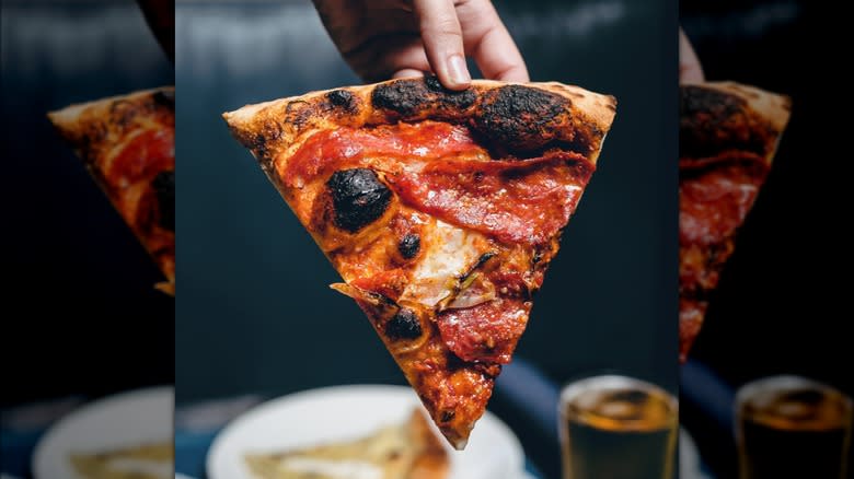 Hand holding slice of pizza