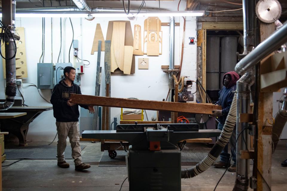 Zhan Cobb, Soteria graduate and current project manager at Soteria Community Development Corporation, 28, right, helps Mike Gambrell, 59, program participant, learn how to cut wooden beams in the shop on Wednesday, Dec. 13, 2023.