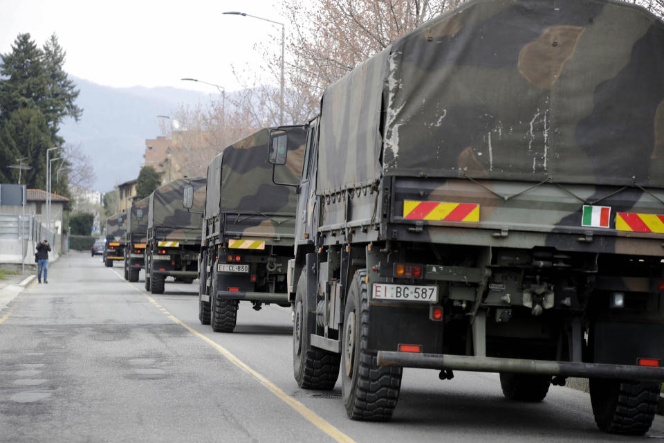 FILE - In this March 26, 2020 file photo, military trucks moving coffins of deceased people leave the cemetery of Bergamo, one of the areas worst hit by the coronavirus infection, on their way to a crematory in some other location as the local crematory exceeded its maximum capacity. Italy marked the anniversary of one of the most haunting moments of its COVID-19 emergency, when Bergamo’s death toll reached such heights that an army convoy had to transport the dead out because its cemeteries and crematoria were full. (AP Photo/Luca Bruno)