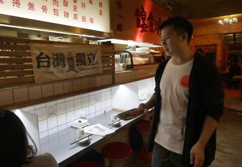 Restaurateur Andy Huang serves guests with a sign reading "Taiwan is An Independent Country " at his restaurant in Taipei, Taiwan, on May 7, 2023. Huang said he's become desensitized to military threats from China. Taiwan’s government is racing to counter China’s military, but many on the island say they don’t share the sense of threat. (AP Photo/Chiang Ying-ying)