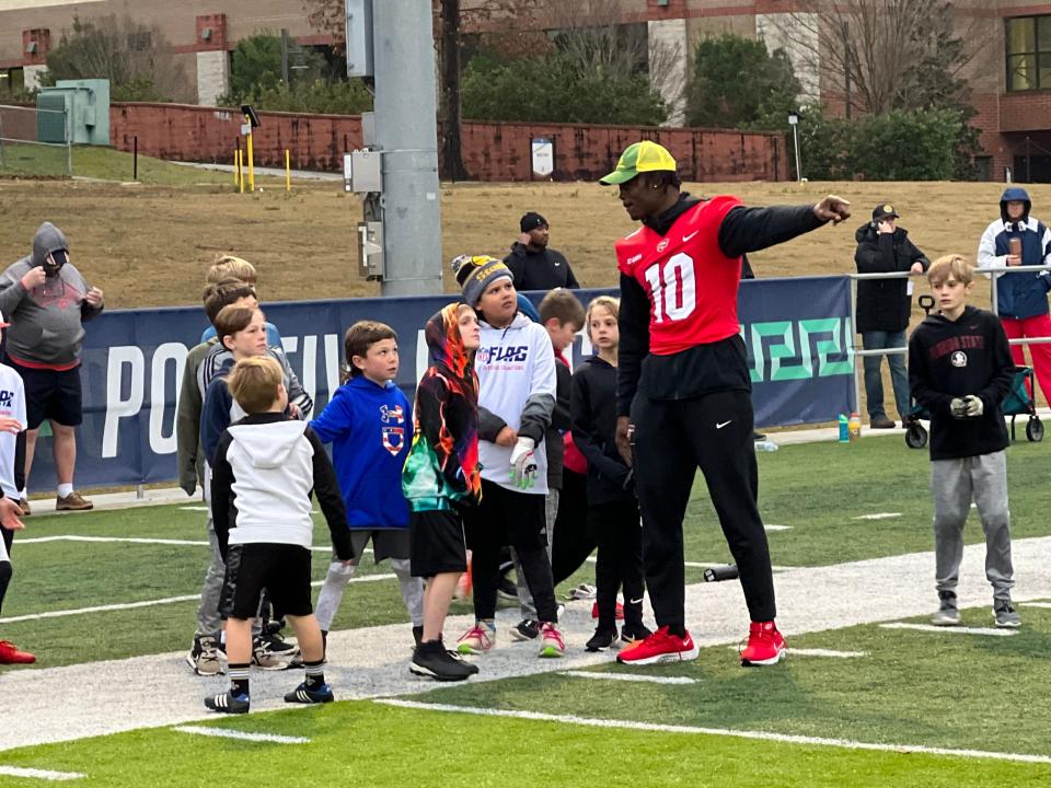 Western Kentucky defensive end DeAngelo Malone instructs area youth during Thursday's Reese's Senior Bowl clinic at UWF's Pen-Air Field.